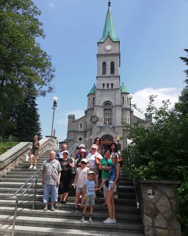  Skupina ľudí stojí na mohutnom schodisku pred kostolom v Zakopanom. 