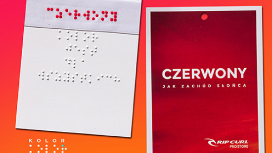 Visačka odevu červenej farby. Na jednej strane je popis v Braillovom písme, na druhej strane je latinkou v poľštine napísaný text: červená ako západ slnka.