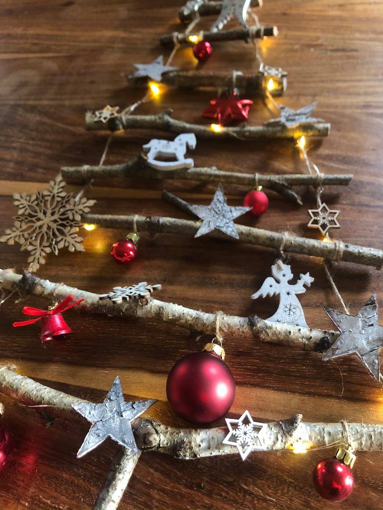 vianočná stromček vyrobený s brezových konárikov pospájaných špagátom a ozdobený vianočnými dekoráciami
