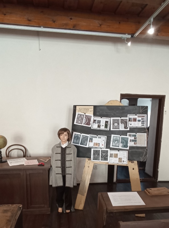Pohľad do miestnosti múzea, pred tabuľou je figúrka žiaka v dobovom oblečení