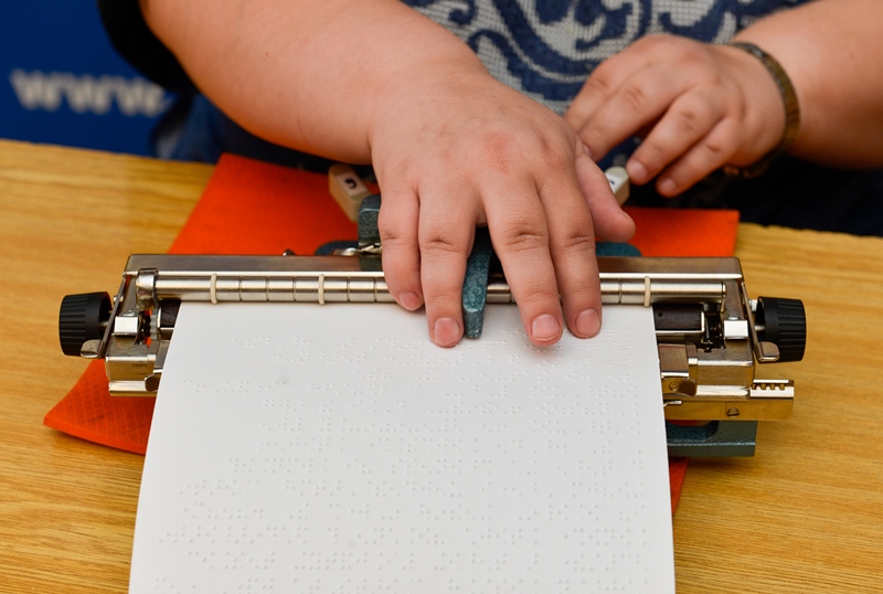 Ženské ruky a stroj na písanie Braillovho písma