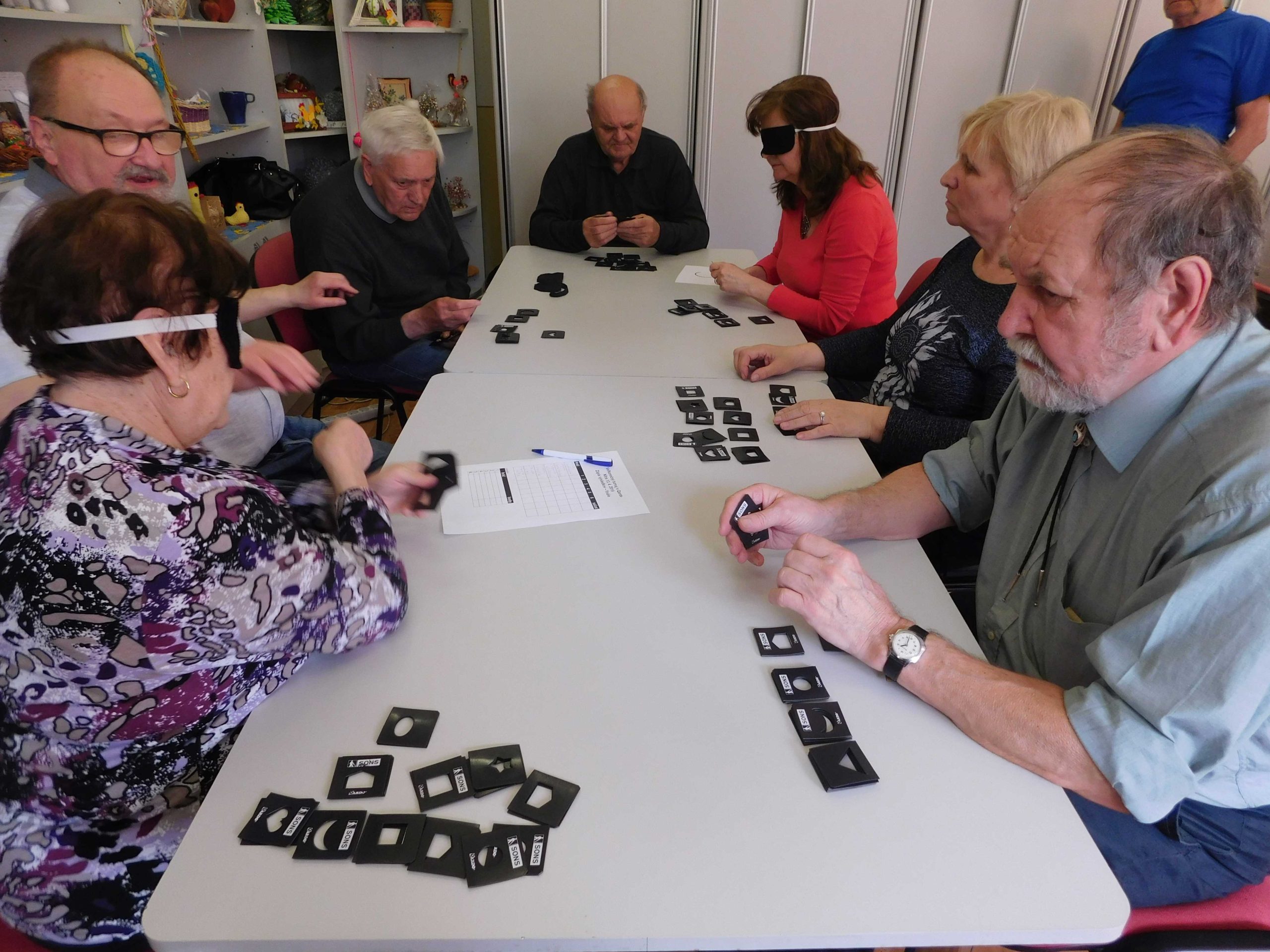 Skupina 7 ľudí za stolom, hrajúci spoločenskú hru Qardo.