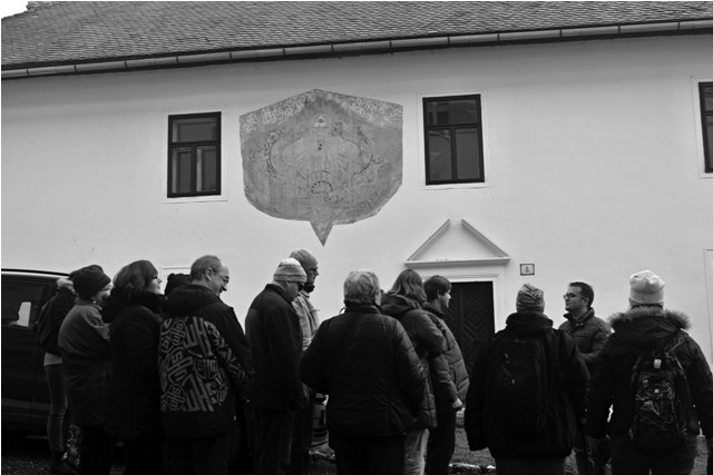 sprievodca podáva výklad skupine návštevníkov pred historickou budovou