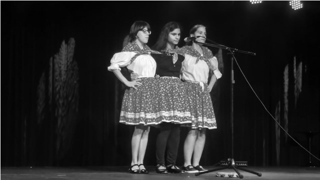 Na pódiu sú tri ženy pred mikrofónom.