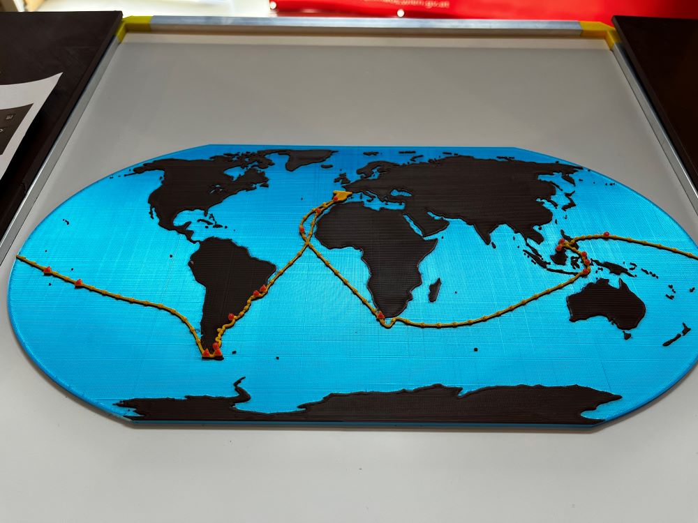 Fotografia 3D platne znázorňuje mapu sveta. Žltou bodkovanou líniou je na nej vyznačená trasa, ktorou sa Magellan plavil. V hornej časti platne je veterná ružica, ktorá v tejto podobe nahrádza kompas a ukazuje svetové strany, z ktorých môže fúkať vietor. 