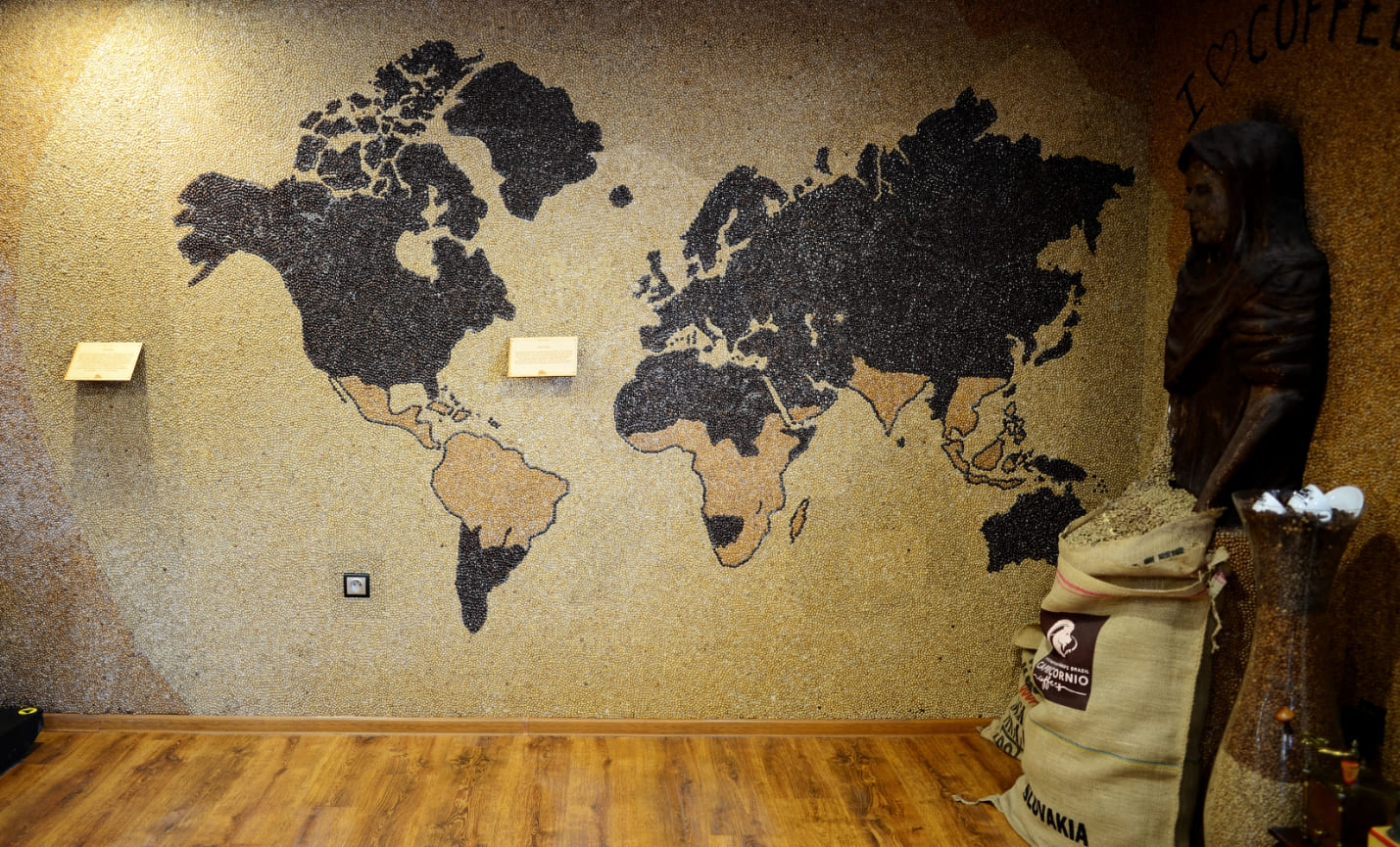 Na fotografii vidíme mozaiku, mapu sveta, vytvorenú zo zrniek kávy. Svetlejšími zrnkami sú znázornené oblasti, kde sa pestuje káva.  