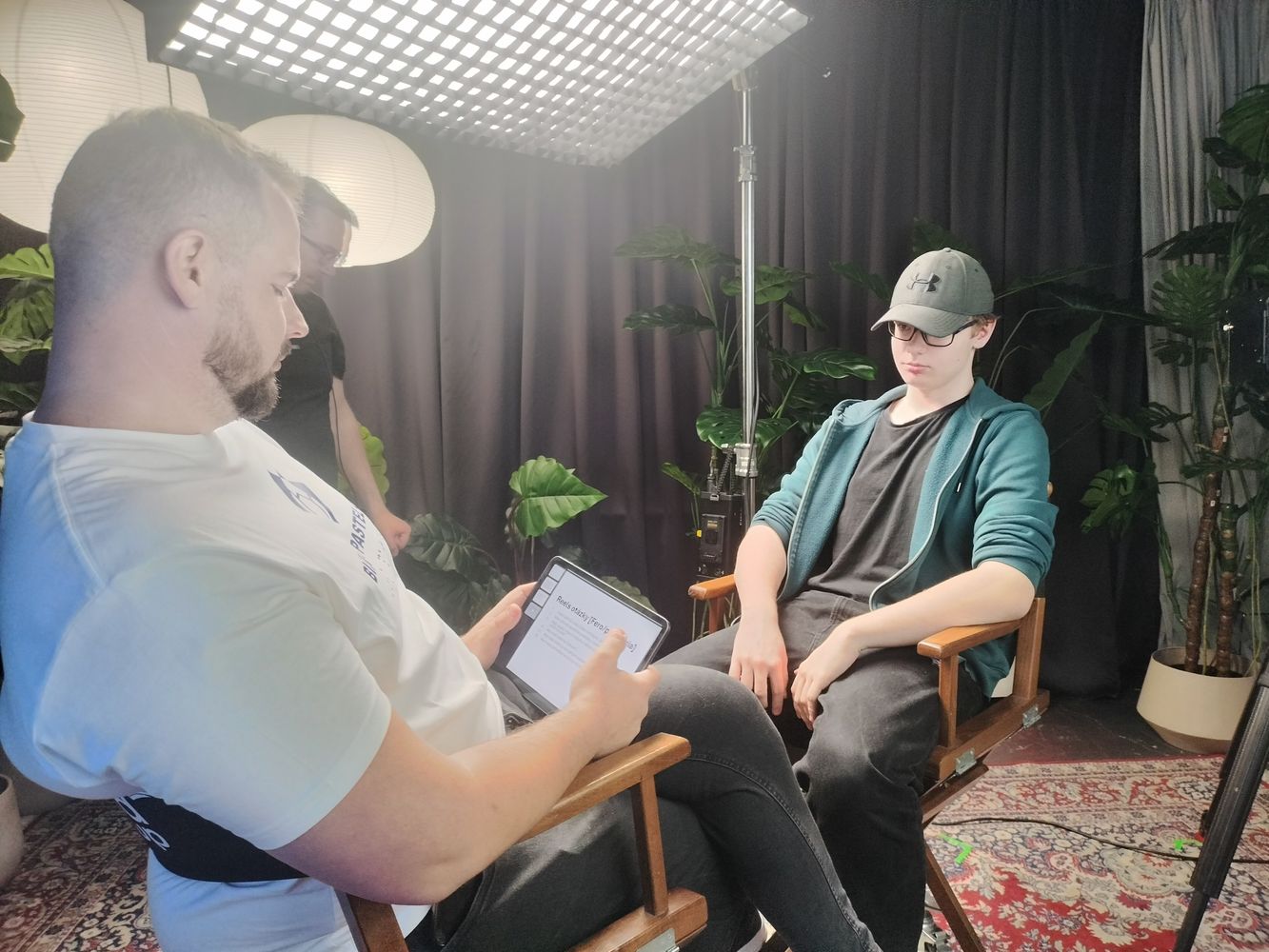 V štúdiu sedia oproti sebe na stoličkách Fero Joke a tínedžer v mikine a šiltovke. Fero Joke sa díva do tabletu. V zábere vidieť reflektor a časti nahrávacej techniky. 