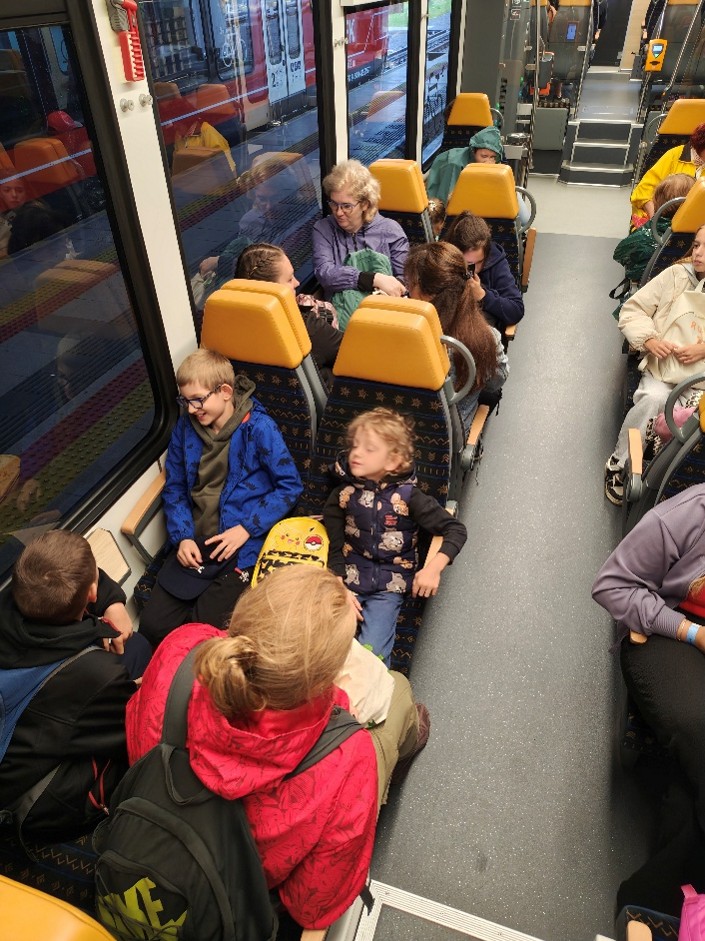 Záber do vozňa vlaku plného detí. 